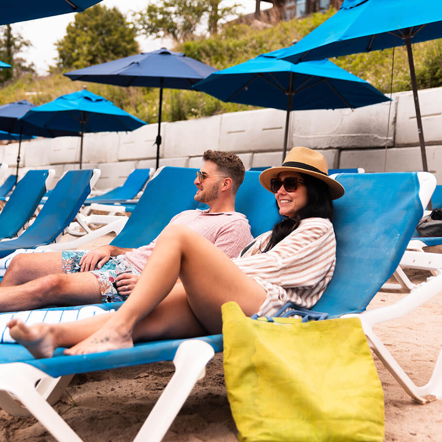 People sitting in lounge chairs in the sand