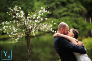 couple kissing on their wedding day with a lush green background