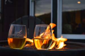 two wine glasses sitting next to open firepit