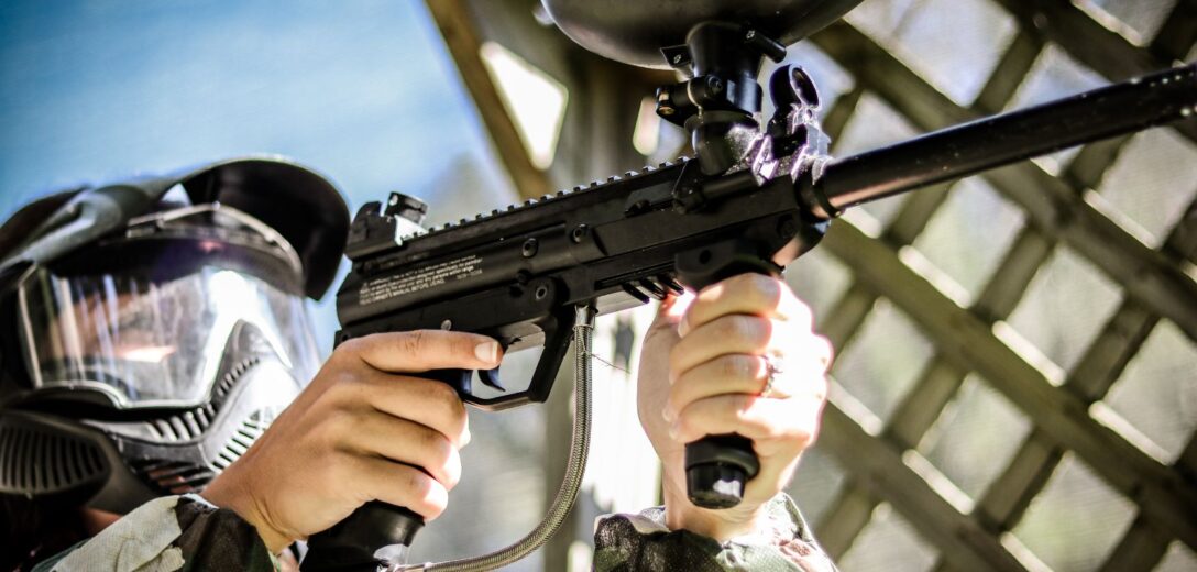 person aiming a paintball gun