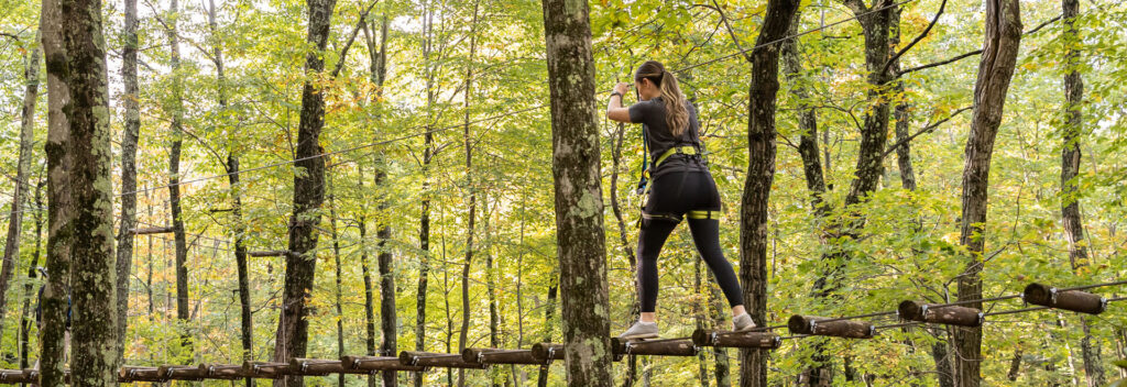 woman walking across treetop adventure course