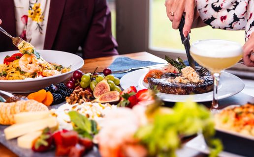 Two people eating at a table full of many food options