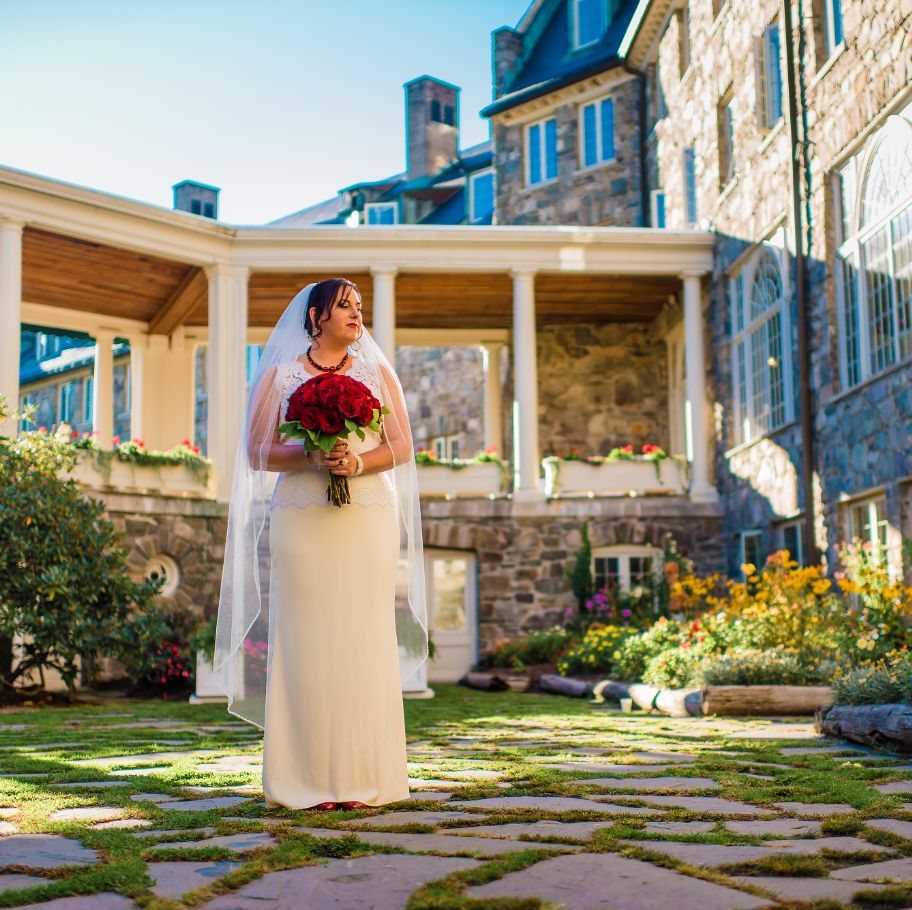 bride standing in the courtyard with red roses